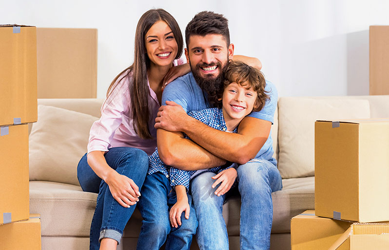 Mother, father and daughter with a SOLD sign in front of their new home