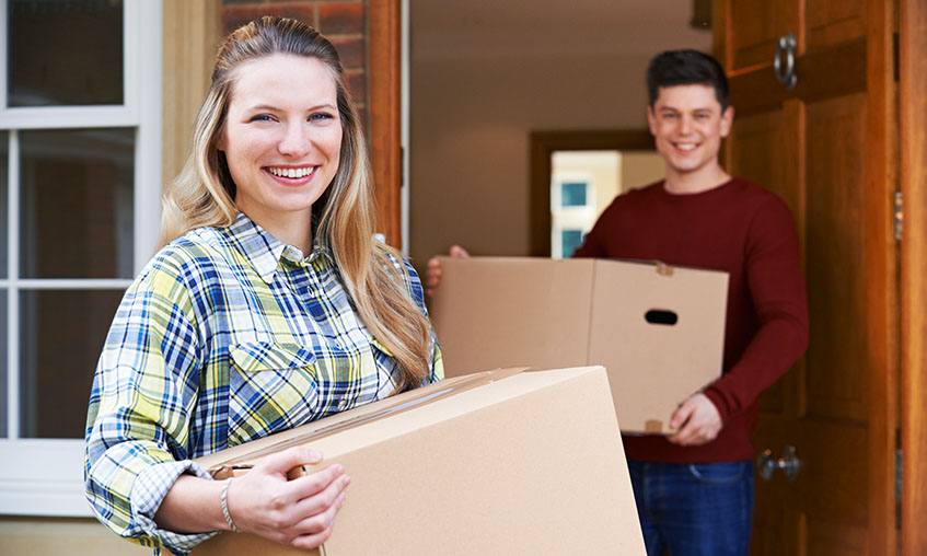 Young couple carrying boxes into new home